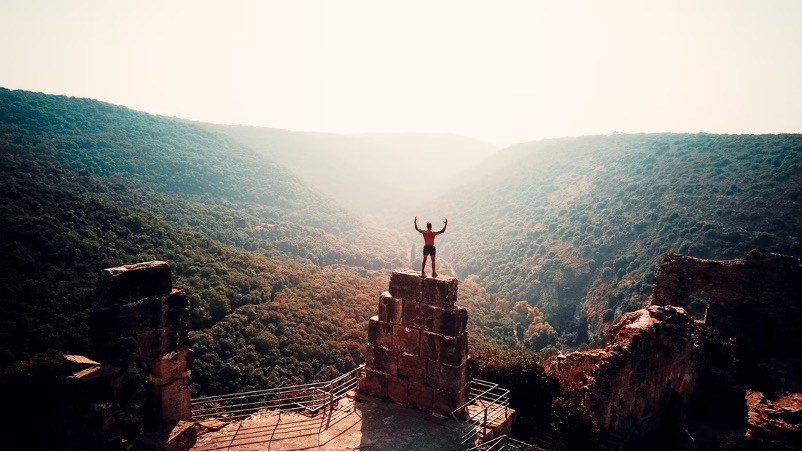 man on top of wall celebrating